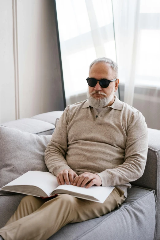 a man sitting on a couch and reading a book