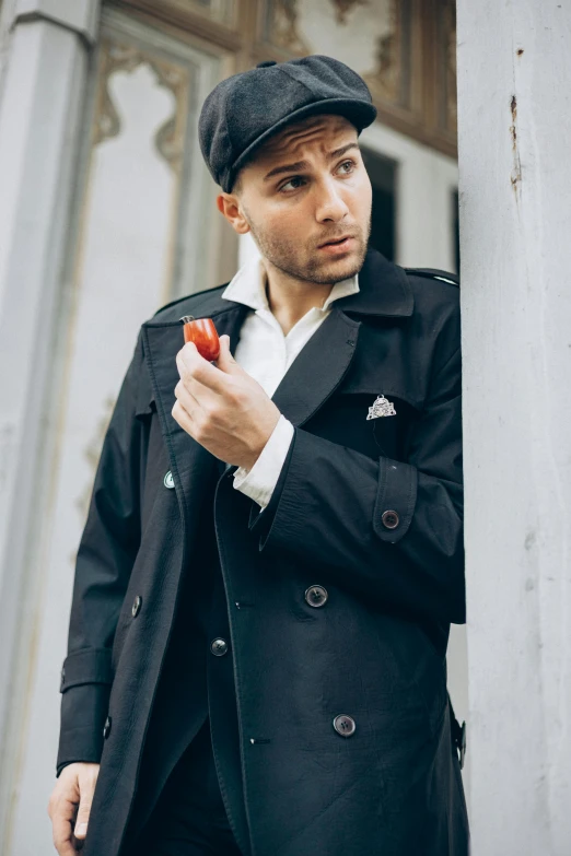 a man holding an apple by a wall