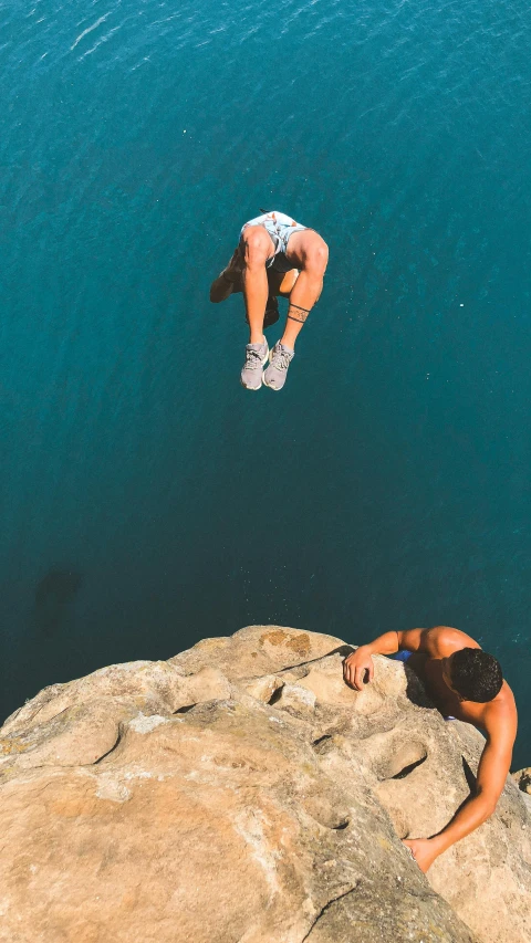 woman diving off a cliff into the water