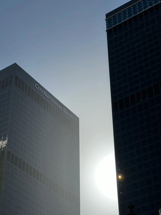 the sun shines brightly behind two building near each other