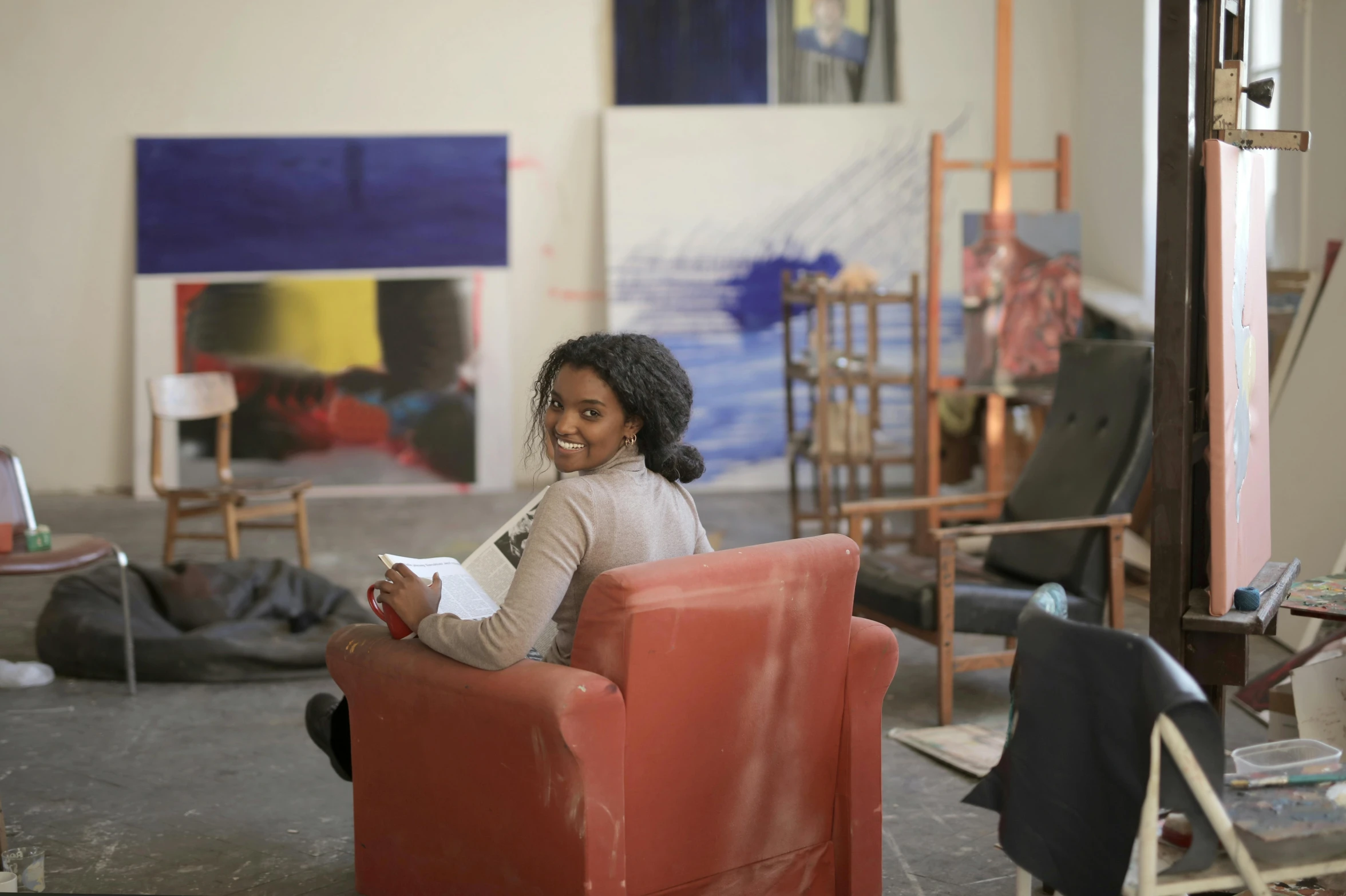 a girl sits in an orange chair while she holds a piece of paper