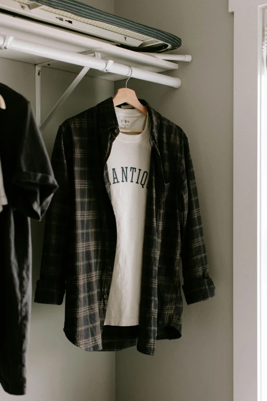 some shirts hanging on a coat rack next to other clothes