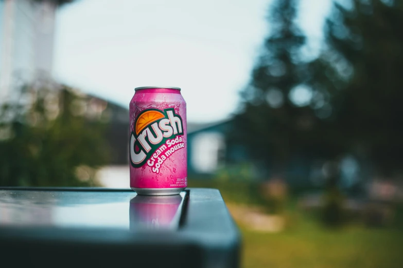 a pink can of soda on top of a metal table