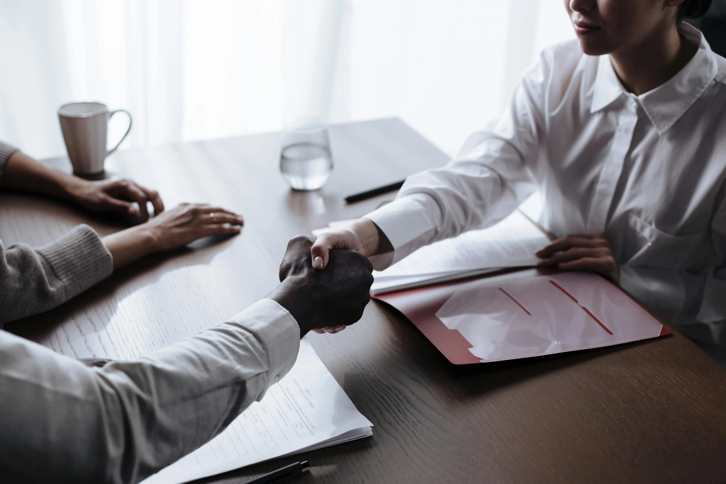 a close up of two people shaking hands over a wooden table