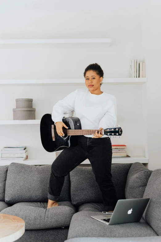 a woman standing with her guitar in the living room