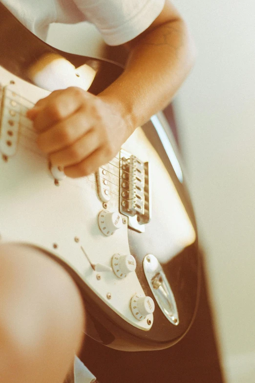 a person playing on a white electric guitar