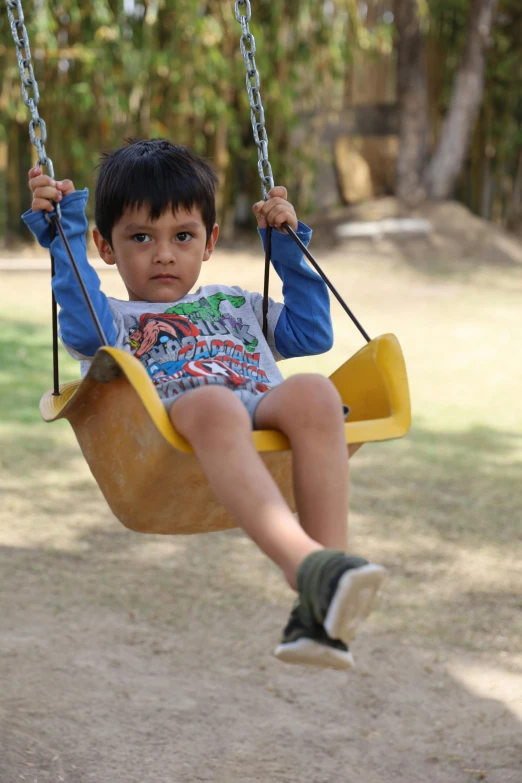 a small boy sitting on a yellow swing