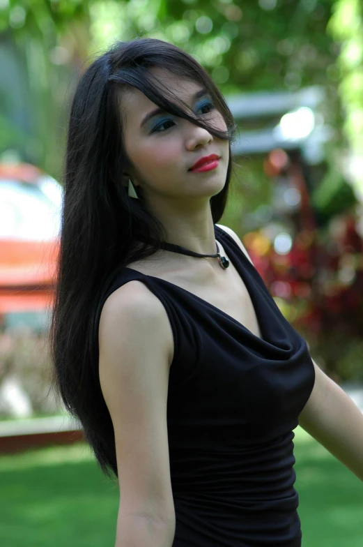 a woman in black dress with red lips standing outdoors