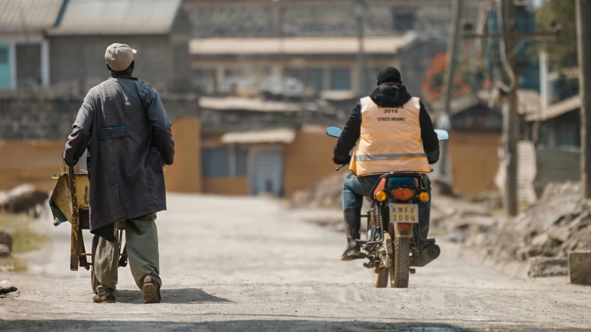 two people are standing on a motorcycle in the street