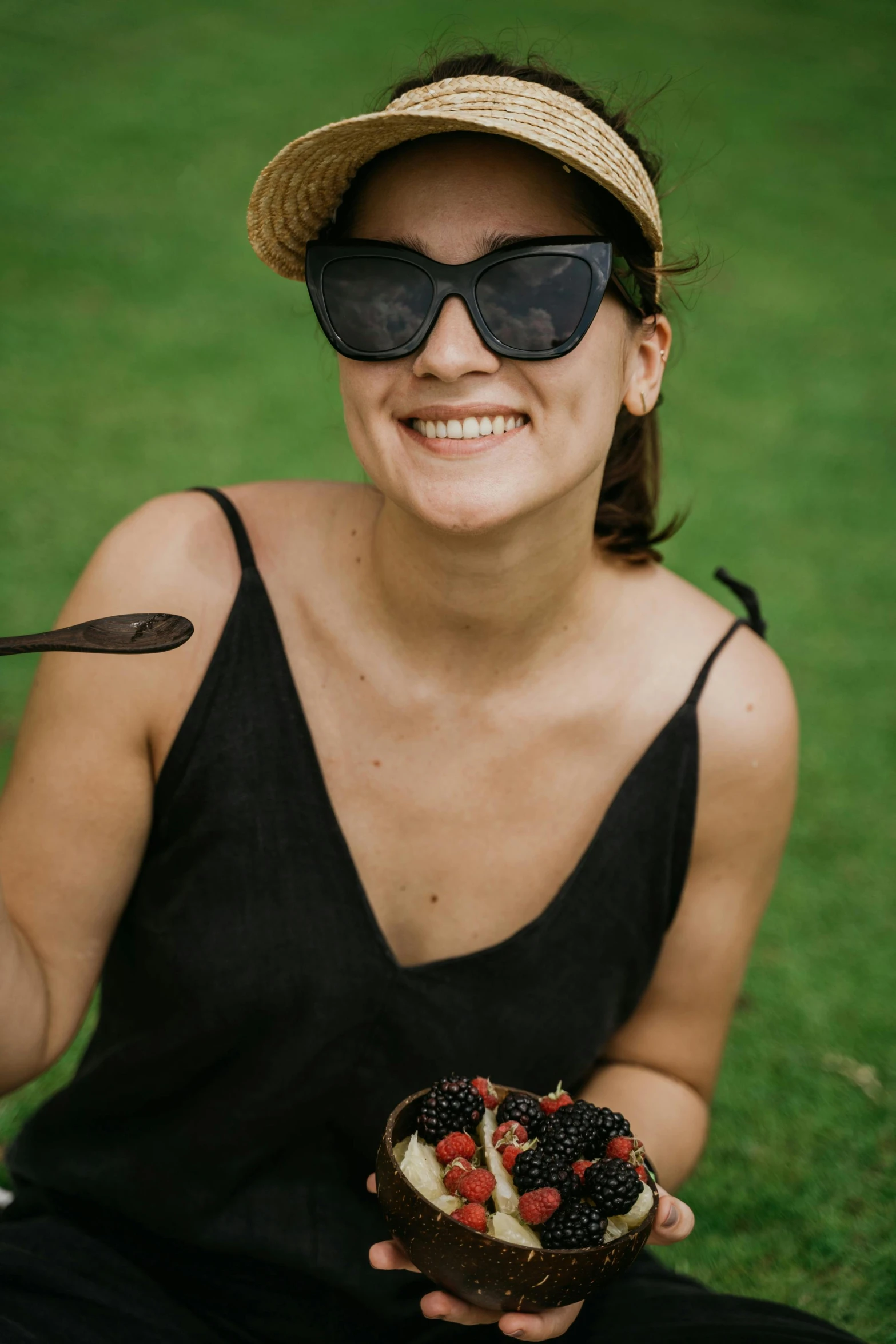 a woman wearing sun glasses holding a piece of cake