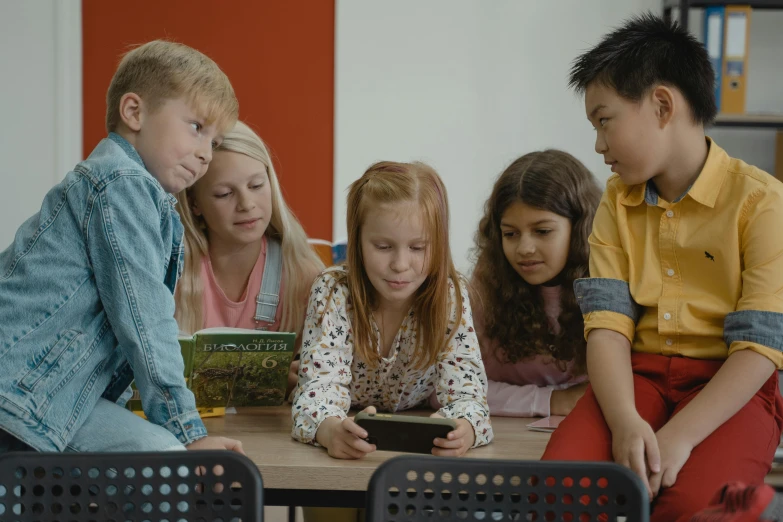 four children reading and writing with the teacher