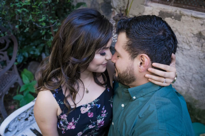 a couple are posing and hugging outside in the day time