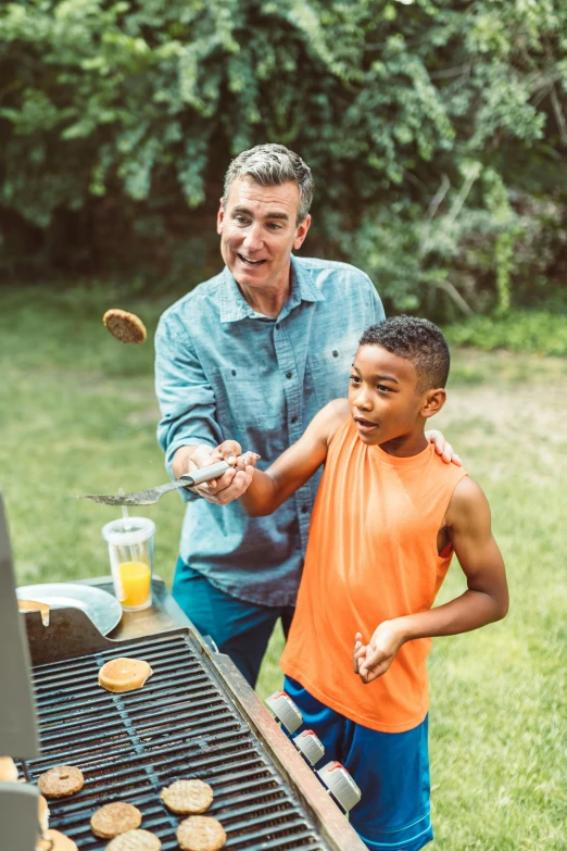 an adult and a small boy grilling together on the grill