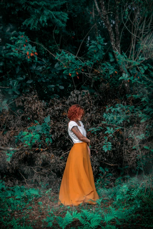 woman in an orange skirt walking through the woods