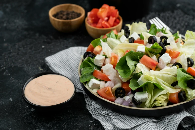 a salad with olives, tomatoes, lettuce and black olives on it