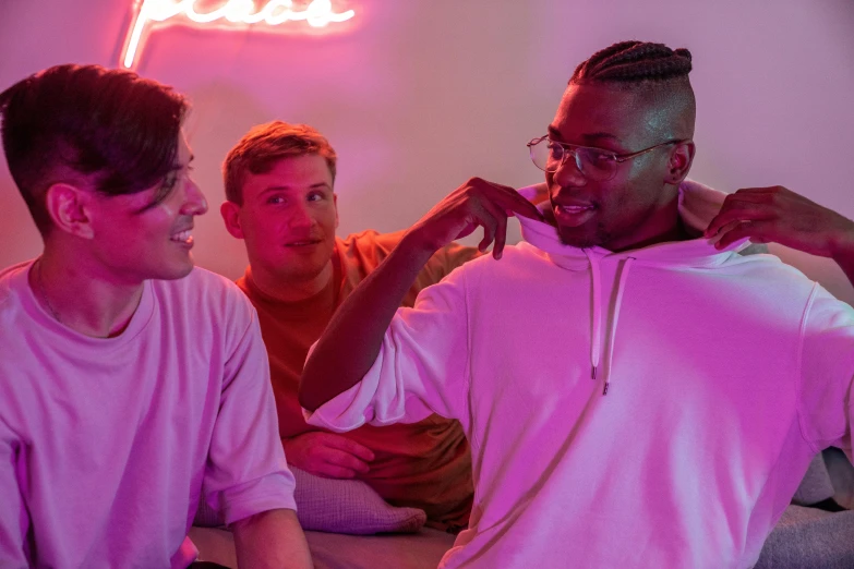 a group of men sitting in front of a neon sign