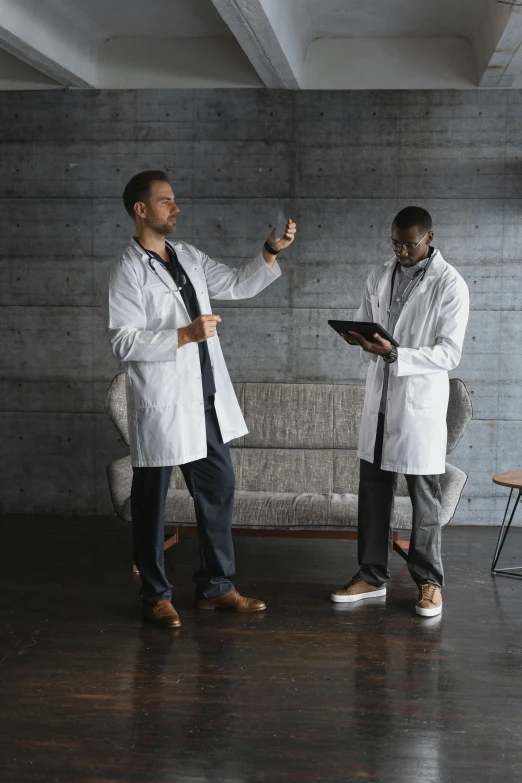 two men are standing together in a gray room