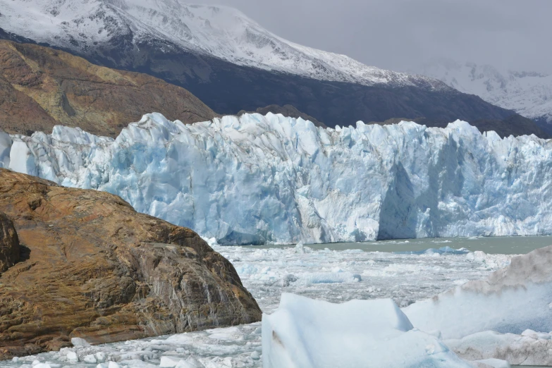 a couple of large glacier walls, with snow on the mountains in the background