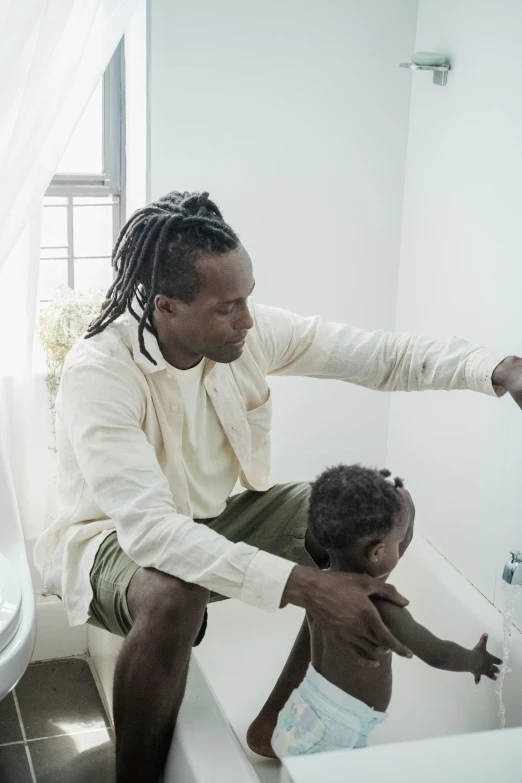 a father and son bathe in a white bath tub