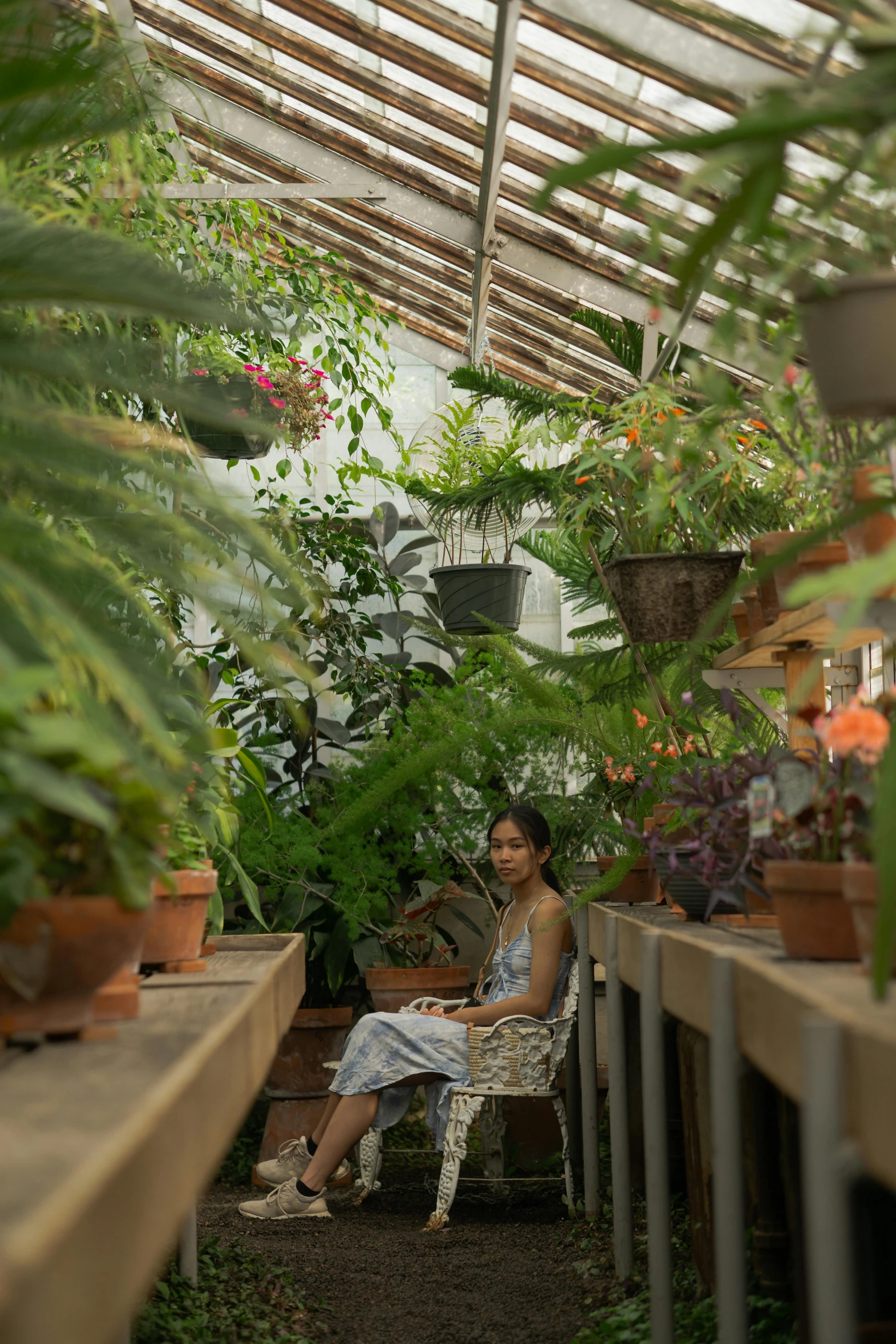 a woman sitting on a bench in a room filled with plants