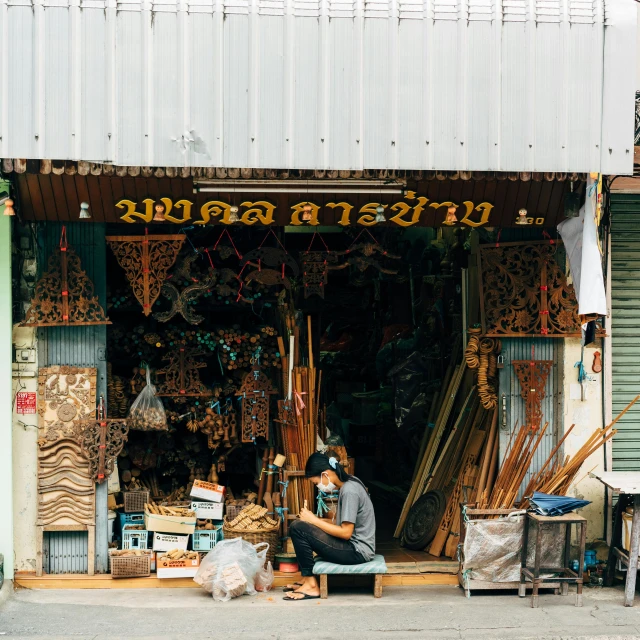 the man sits in the doorway of a shop selling oriental items