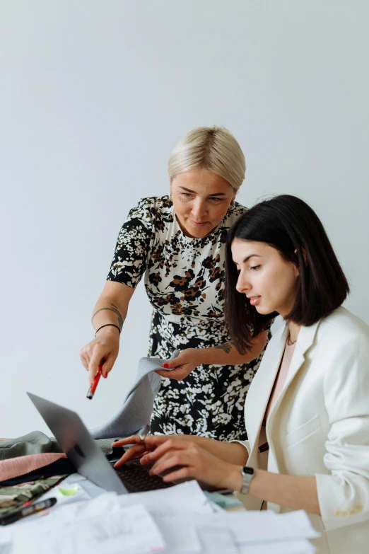 a woman at a desk in front of another woman who is using a laptop