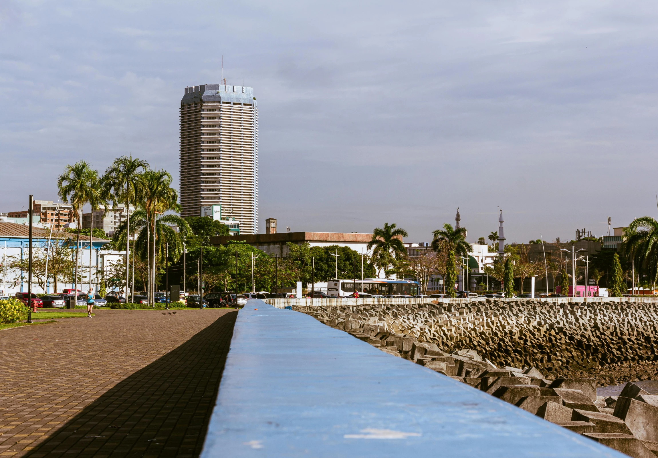 a long blue bench sits in the middle of a pathway