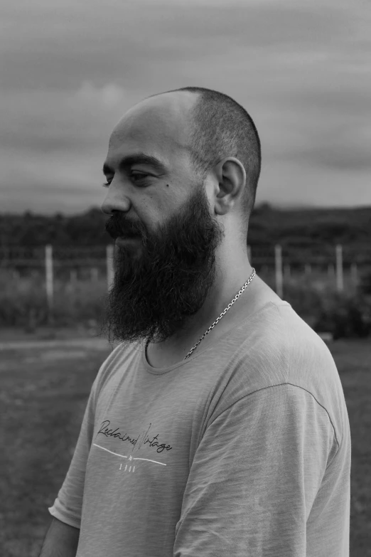 a man with a beard and moustache stands in front of a field