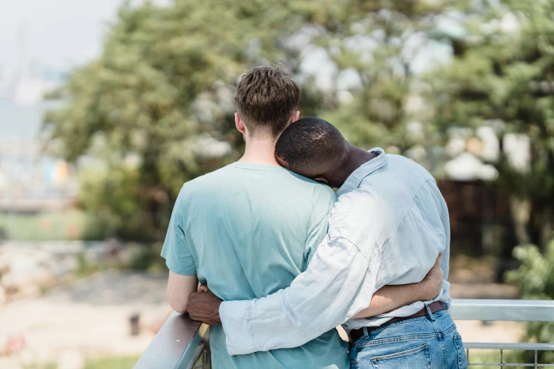 two men hugging while standing next to a rail