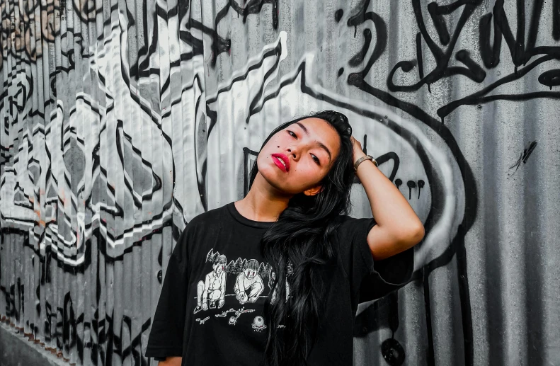 a woman with her eyes closed stands in front of some graffiti