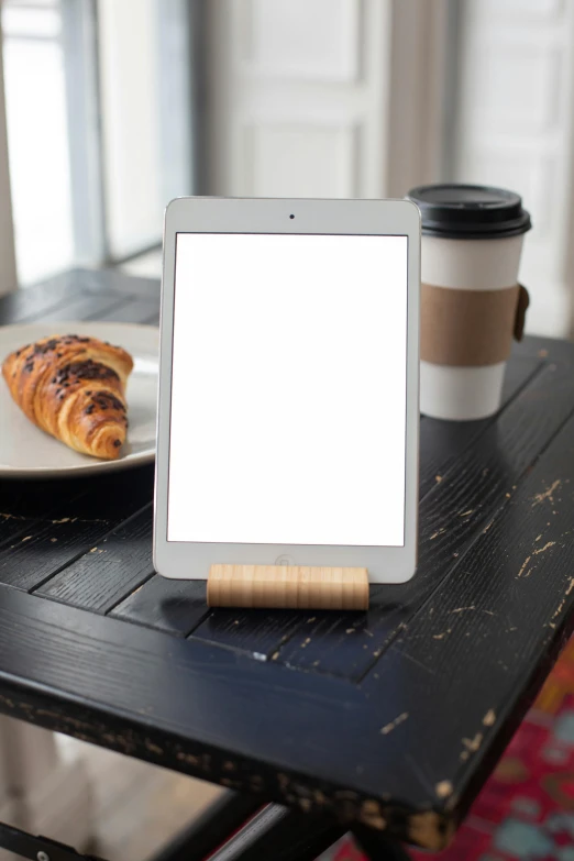 a tablet next to two coffee cups on a table