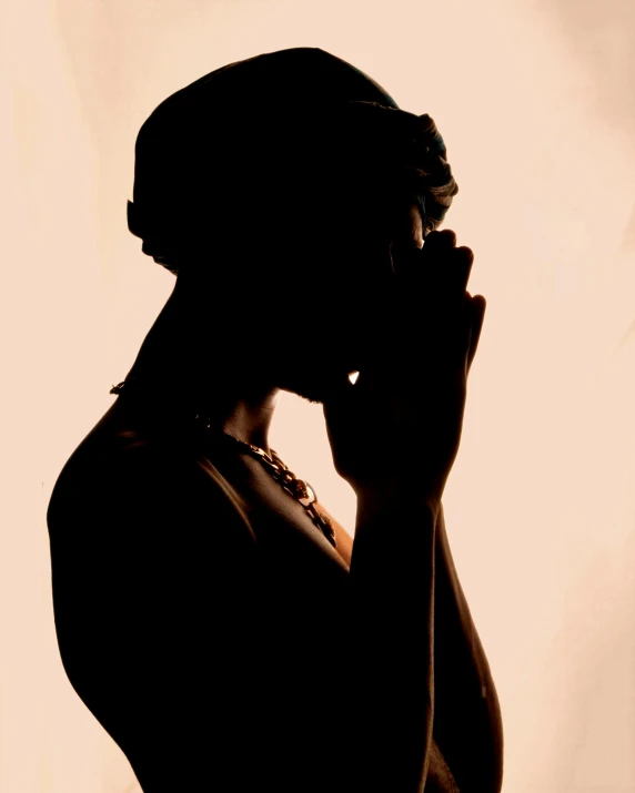 a woman with her hand in her mouth, standing against a white backdrop