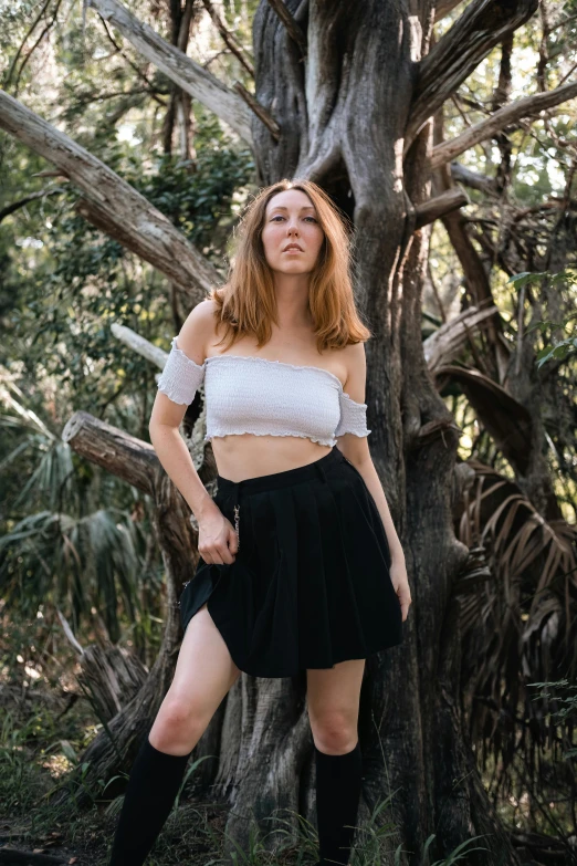 a woman posing near trees in a white crop top