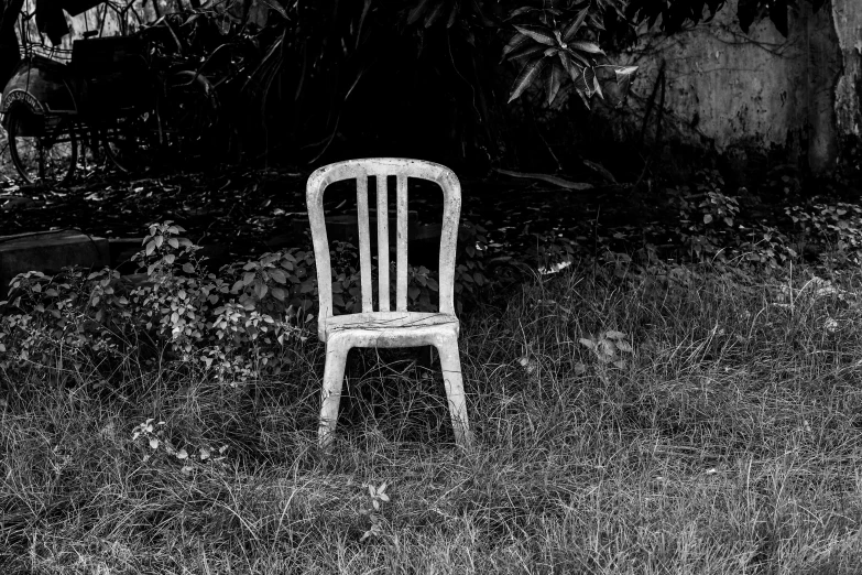 an old white chair sitting in the grass next to a tree