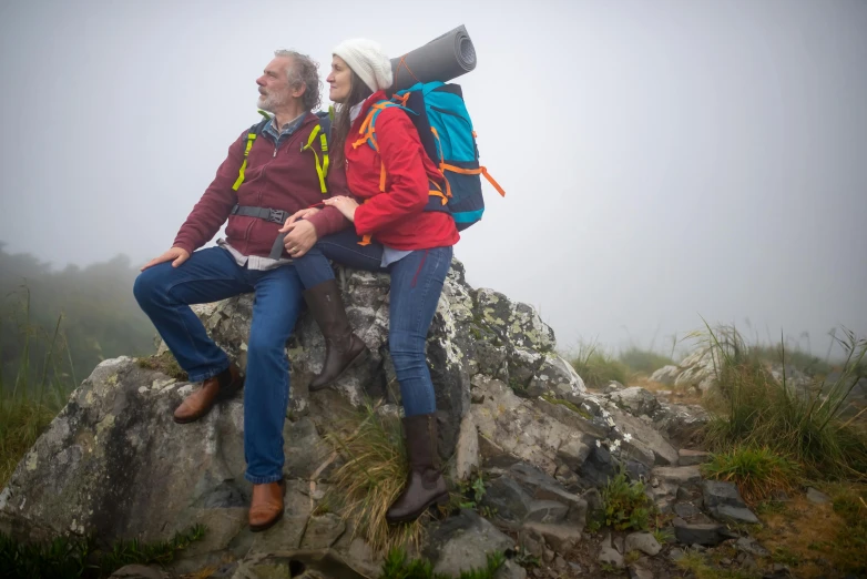 the two hikers are sitting on rocks with backpacks