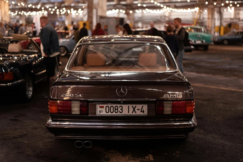 a brown mercedes sitting next to other cars in a garage