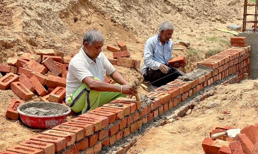 a couple of men putting bricks into a bucket