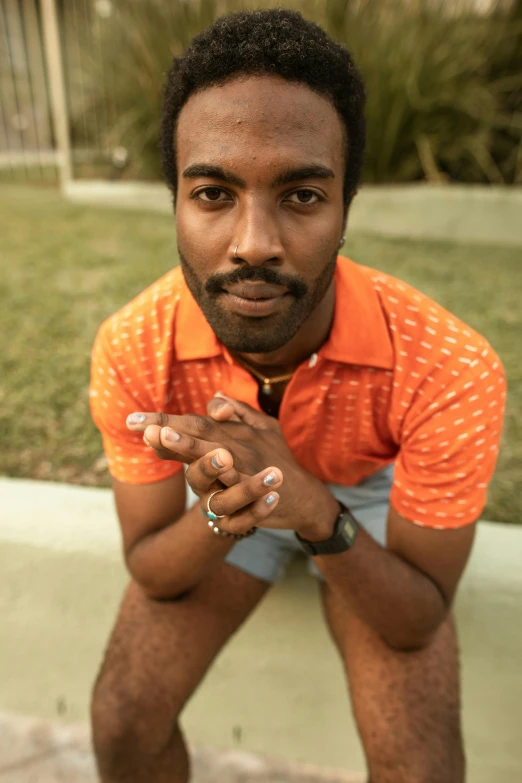 a close up of a person crouching wearing an orange shirt
