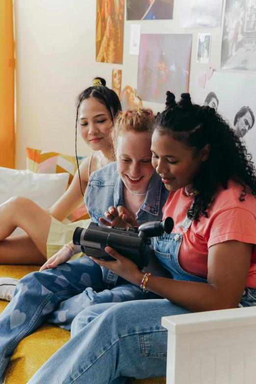 three women sitting together, looking at a device