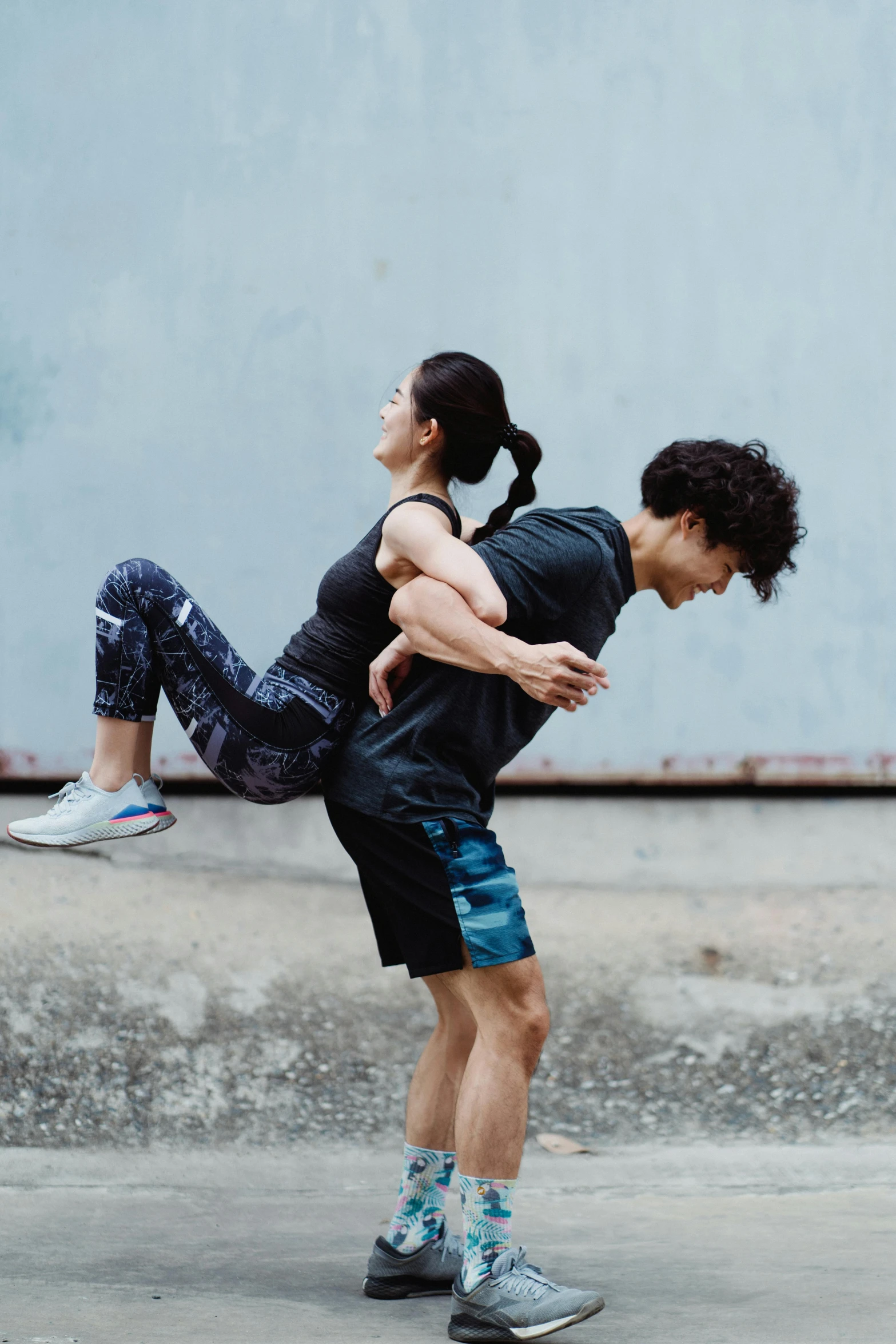 a man holding a woman that is walking across a concrete street