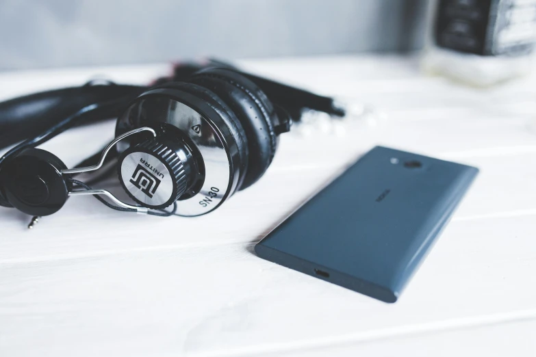 headphones and a cellphone sitting on a white table