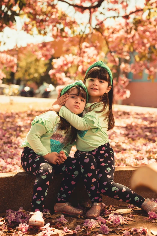 two small girls sitting on steps under a cherry tree