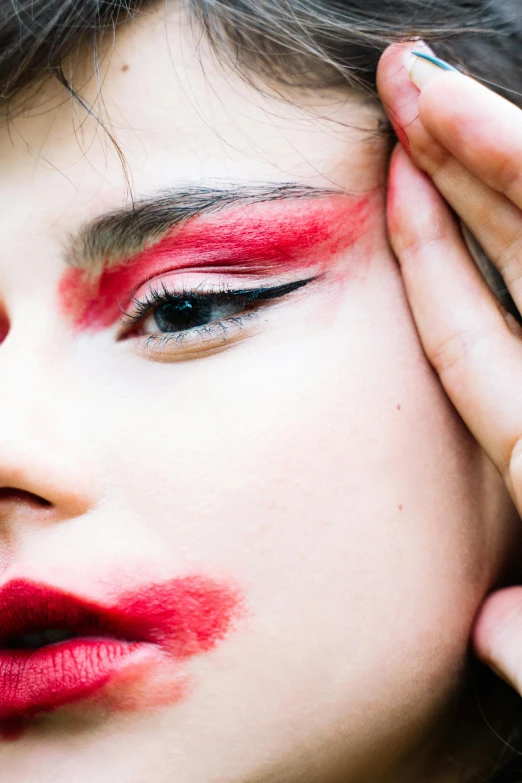 a young woman is putting on makeup with a red lip