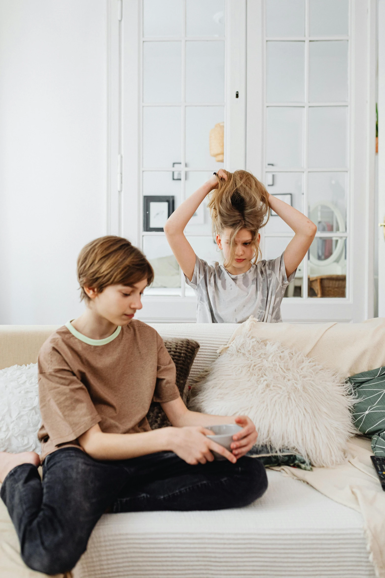 two girls sitting on a bed and one has her hair pulled back