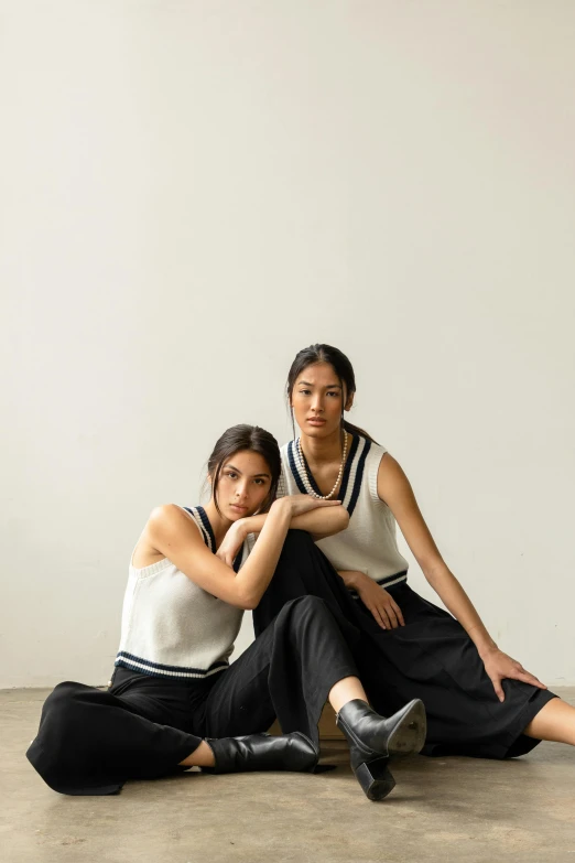 two young women in black and white shirts and black pants pose for a pograph