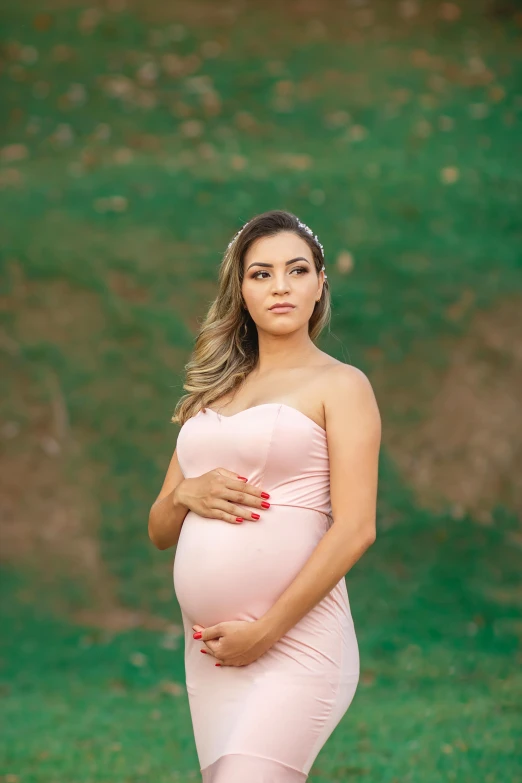 an pregnant woman in pink poses for a po