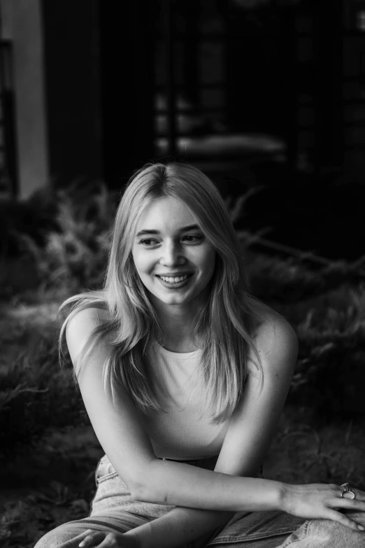 a smiling woman sitting on a bench in front of a building