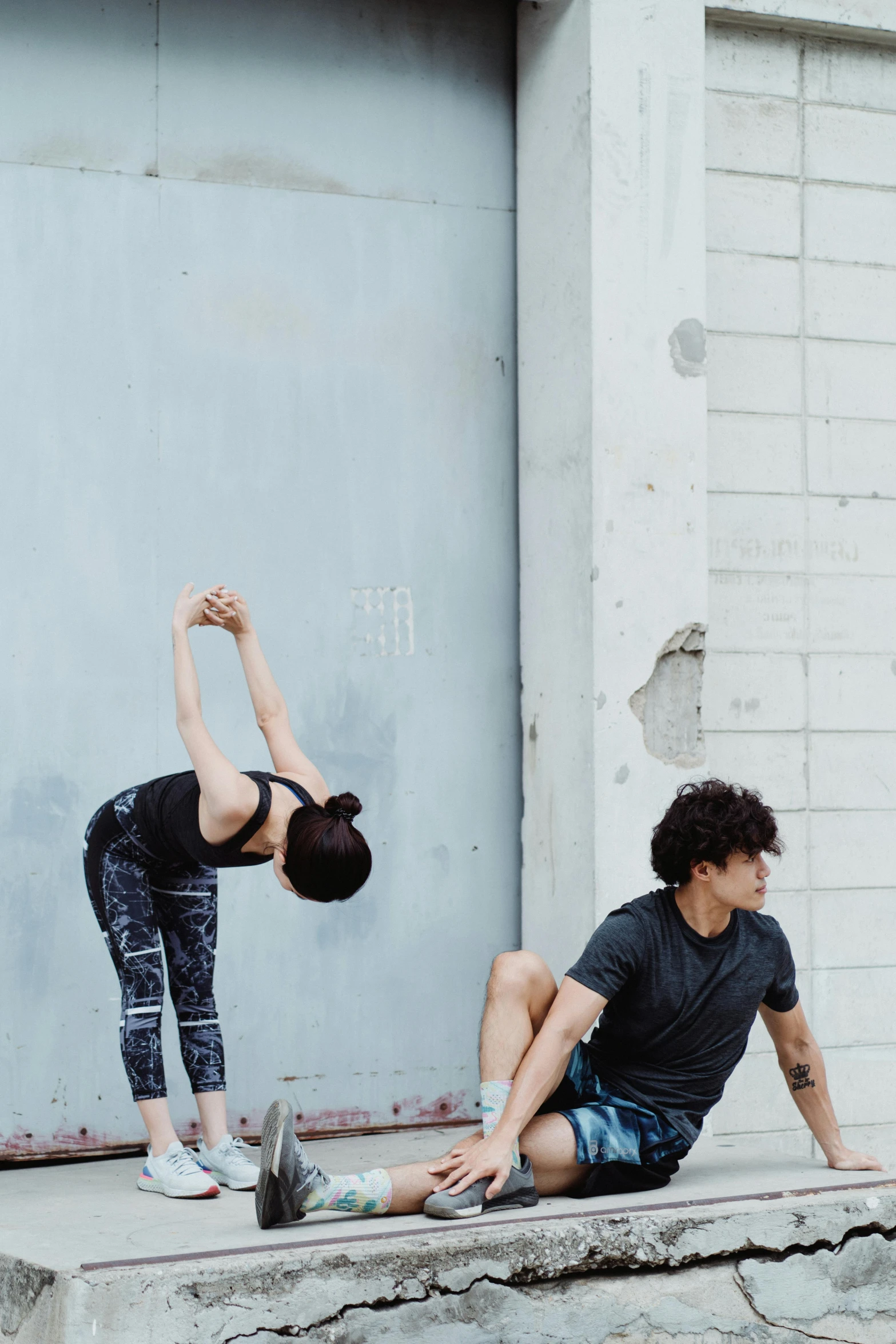 two people stretching with one person sitting on the ground