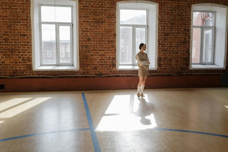 woman standing in a brick hall looking out two windows