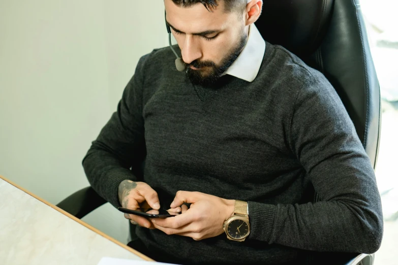 a man looking at his cell phone while sitting in an office chair